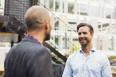 Happy businessman talking to male colleague at office yard