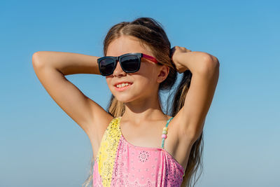 Cheerful girl in a swimsuit holds her hair with her hands at the resort.