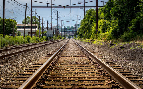 Railway tracks by trees against sky