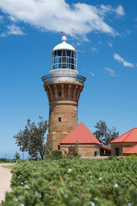 Low angle view of lighthouse by building against sky