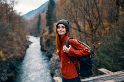 Portrait of young woman standing against trees during winter