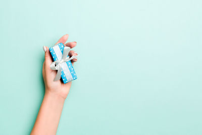 Cropped hand holding gift against blue background