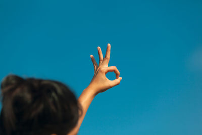 Woman gesturing against blue sky