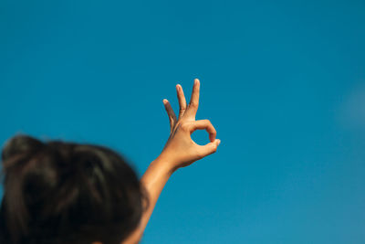 Rear view of woman hand against blue sky