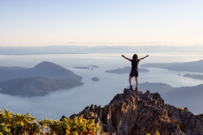 Rear view of person standing on rock against sky