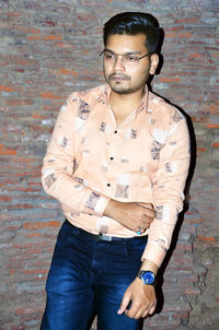 Portrait of young man standing against wall