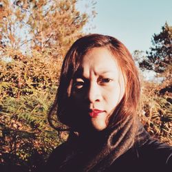 Close-up portrait of young woman against trees