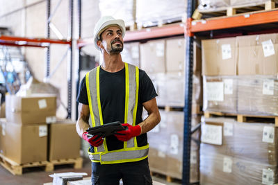 Smiling worker examining inventory with tablet pc at warehouse