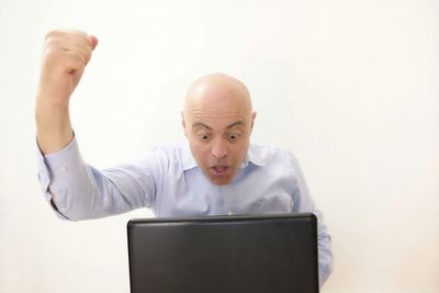 Businessman clenching fist while using laptop in office