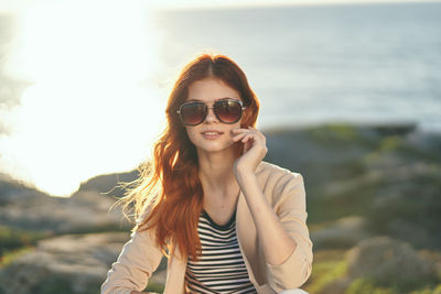 Portrait of smiling young woman against sky