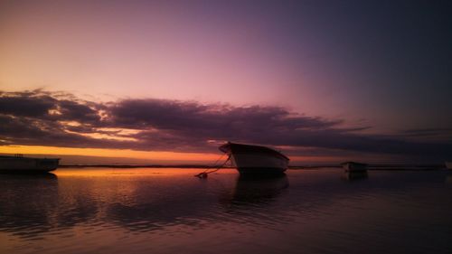 Silhouette boat in sea against sky during sunset