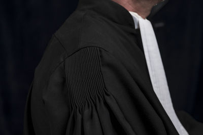 Side view of lawyer standing against black background