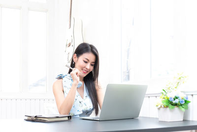 Young woman using mobile phone while sitting on table