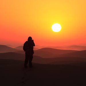 Silhouette man standing against orange sky during sunset