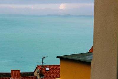 Buildings by sea against sky