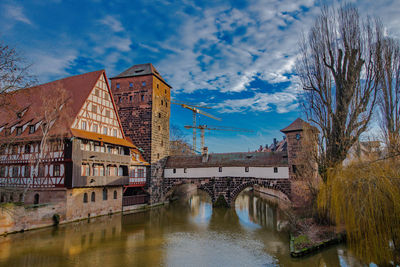 Bridge over river amidst buildings against sky