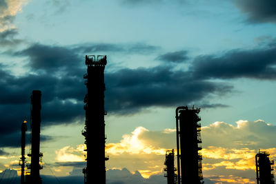 Low angle view of silhouette smoke stack against sky during sunset