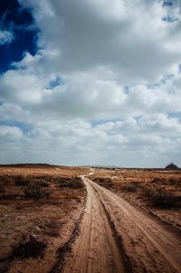 Road amidst field against sky