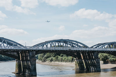 Plane flying over barnes railway bridge on a bright sunny day, london, uk.
