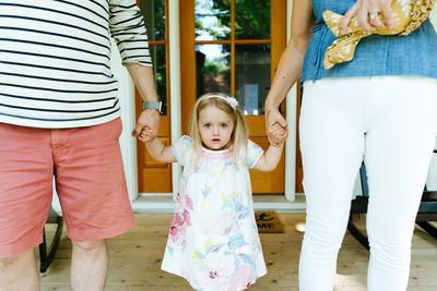 Cropped closeup of a toddler girl holding her parents hands