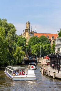 Boats in canal by buildings against sky