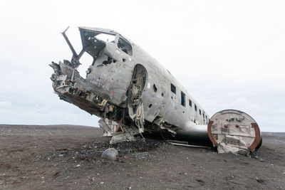 Abandoned airplane on airport runway against sky