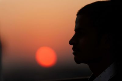 Close-up portrait of silhouette man against orange sunset sky