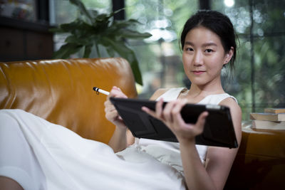 Portrait of smiling woman using digital tablet while relaxing on sofa