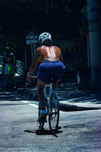 Rear view of man riding bicycle on street