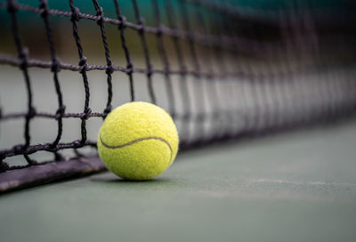 Close-up of green ball by net on court