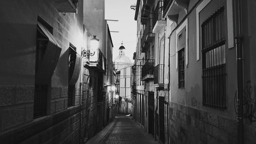 Empty alley amidst buildings against church