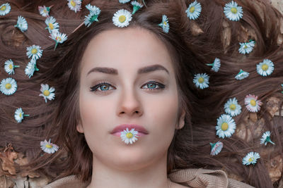 Close-up portrait of beautiful woman lying down with flowers on hair outdoors