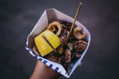 Close-up of hand holding fried squids in box