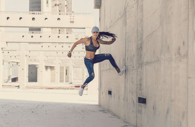 Full length of young woman jumping in city