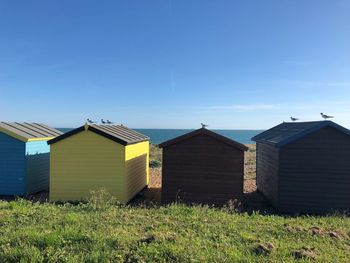 Buildings on field against clear blue sky