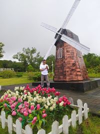 Woman standing by flowering plants against sky