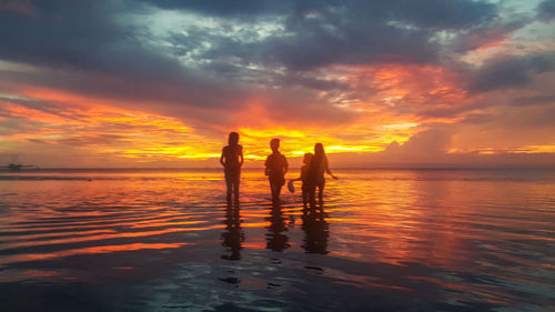 Silhouette people on beach during sunset