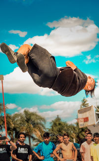 Low angle view of man holding hands against sky