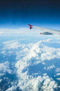 Airplane flying over cloudscape against blue sky