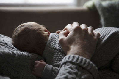 Midsection of father embracing baby while lying at home