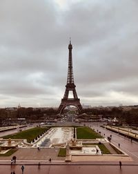 Communications tower in city against cloudy sky