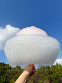Low angle view of woman holding umbrella against clear blue sky