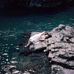 Young woman on rock at shore