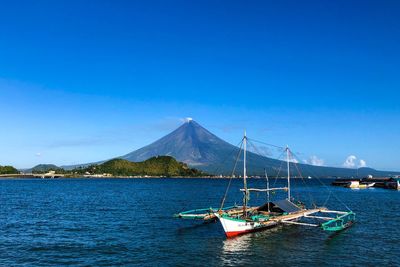 Sailboats in sea against blue sky