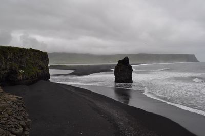 Rock formation on beach against sky