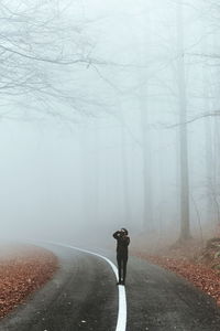 Woman standing on road during foggy weather