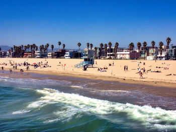 People at beach against clear blue sky