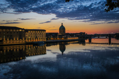 Reflection of illuminated buildings in river during sunset