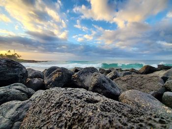 Rocks on beach against sky during sunset