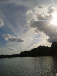 Sun shining through clouds over sea